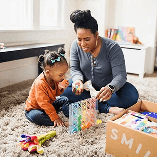 Child and mother playing with the Drop & Match Dot Catcher from The Helper Play Kit