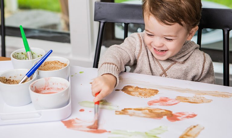 Toddler painting on a white piece of paper