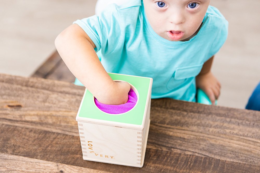 Toddler putting their hand in the Magic Tissue Box by Lovevery