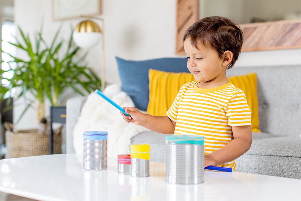 Toddler standing in front of a few canisters with a wooden stick