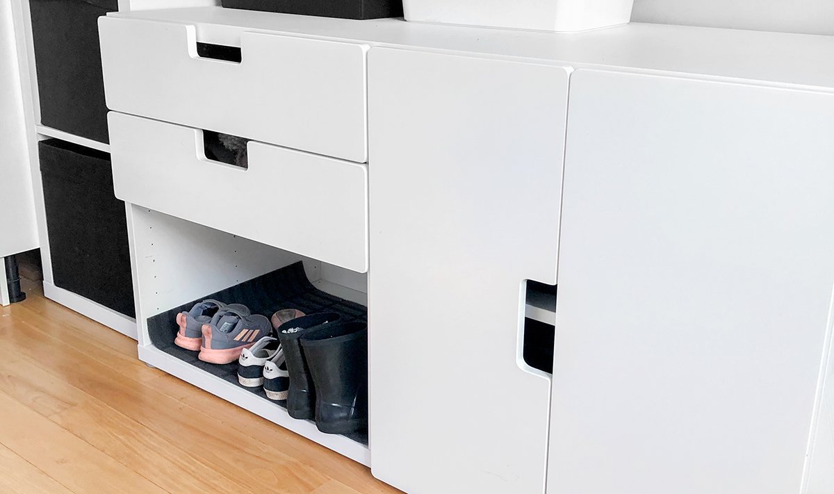 Cabinets and drawers in an entry way with an open spot for shoes