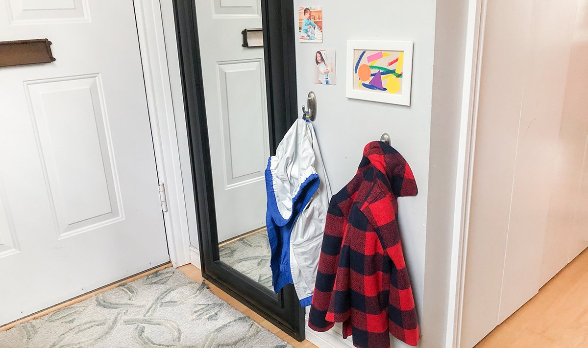Two hanging jackets and a mirror next to the front door